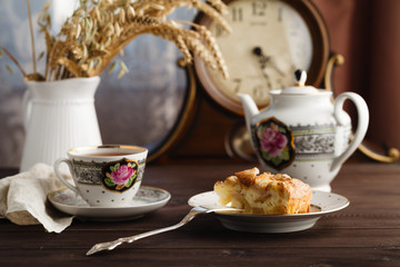cup of hot tea, a tea pot and a part of an apple pie on a table