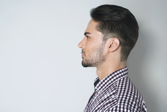Side view of handsome young man. Beautiful profile of brunette man in checkered shirt against light grey background