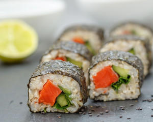 Healthy homemade sushi rolls with brown rice, fish and green vegetable rolls.