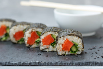 Healthy homemade sushi rolls with brown rice, fish and green vegetable rolls.