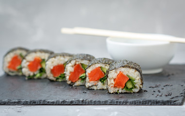 Healthy homemade sushi rolls with brown rice, fish and green vegetable rolls.