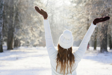 Woman on vacation outdoors, standing back with hands up