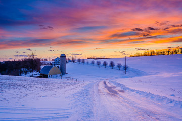 Sunset over a snow covered road and a farm in a rural area of York County, Pennsylvania.