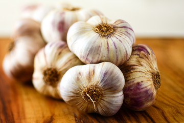 bunch of whole pink garlic cloves on a wooden board