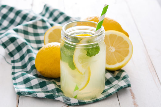 Lemonade drink in a jar glass on white wooden background. Copyspace.
