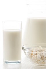 Milk in a glass and jug, cottage cheese in a bowl, on a white table, in a high key, close-up