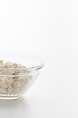 Cottage cheese in a bowl, on a white table, in a high key, close-up with place for text