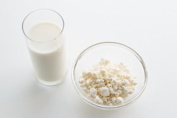 Milk in a glass, cottage cheese in a bowl, on a white table, in a high key, close-up with place for text