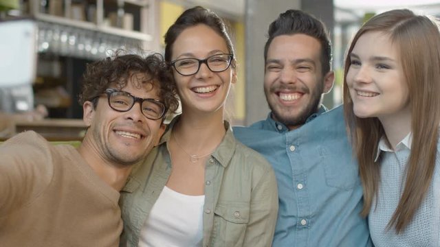 Group of Young Smiling Mixed race People Doing Selfie with Phone in Coffee Shop. Shot on RED Cinema Camera 4K (UHD).
