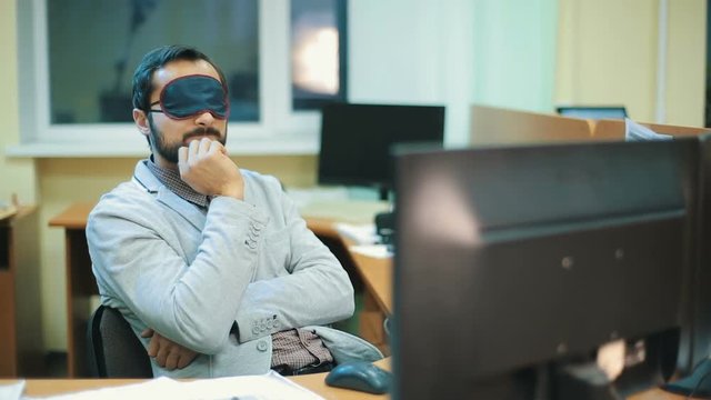 Executive with blindfold sleeping at work