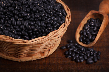 Black beans in scoop on wooden background