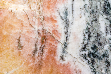 Risse und dunkle Einschlüsse im rosafarbenen Marmorgestein