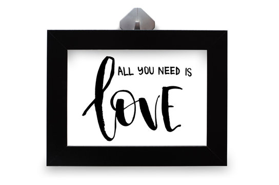 All you need is loveInspirational quote, handwritten text. Modern calligraphy. Black wooden frame. Close-up