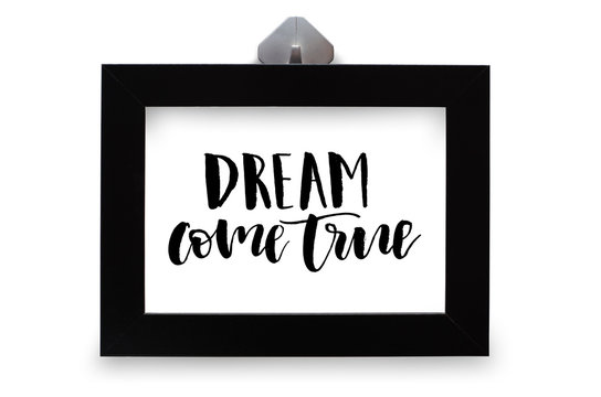 Dream come true. Inspirational quote, handwritten text. Modern calligraphy. Black wooden frame. Close-up
