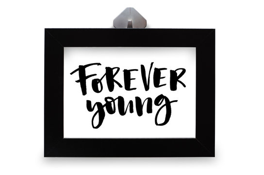 Forever young. Inspirational quote, handwritten text. Modern calligraphy. Black wooden frame. Close-up