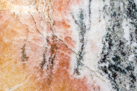 Risse und dunkle Einschl&uuml;sse im rosafarbenen Marmorgestein