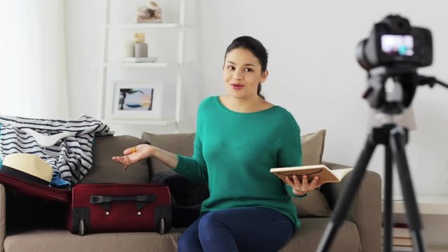 woman with travel bag recording video at home
