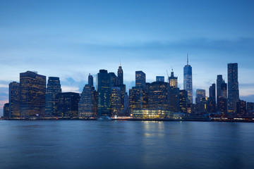 Fototapeta na wymiar New York city skyline with illuminated buildings in the blue evening hour