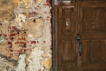 Grunge background - mangy wall with cracks, old wooden door. Textured surface