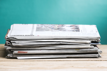 Newspapers folded and stacked on wooden board