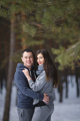 Winter snow couple love story in the forest. Happy romantic smiling lovers hugging in the snowy winter outdoors.People and love concept. Young couple of families