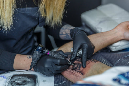 A tattooist woman is making  a tattoo with a tattoo machine