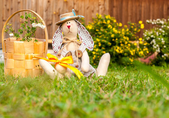 Easter toy rabbit with basket and colorful easter eggs sitting on natiral grass. Happy Easter greeting concept