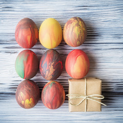 Painted Easter eggs and gift box over wooden background