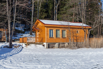 Wooden Russian bath on the shore of a winter lake