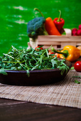 Arugula leaves in bowl. Fresh salad. Natural raw vegetables. Organic bio food on rustic wooden table.