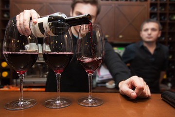 sommelier pouring red wine into a glass - obrazy, fototapety, plakaty