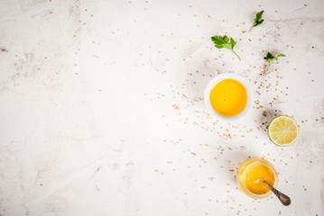 Ingredients for cooking healthy light dressings for vegetable salad: lemon (lime), olive oil, mustard, greens, on white concrete table, copy space top view