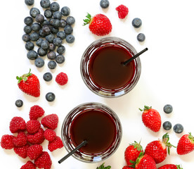 Two glasses of strawberries, raspberries, blueberries juice isolated on white.