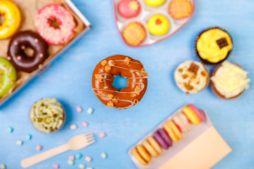 Caramel glazed donut, cupcakes and macaroons. Sweet dessert. Cakes with buttercream. Almond macaron cookies. Delivery box.