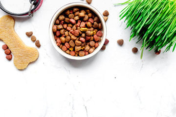 dry dog food in bowl on stone background top view