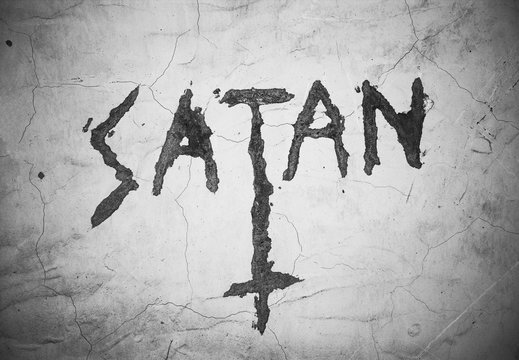 Text Satan an upturned christian cross - writing and symbol on the cracked wall. Sign and expression of satanism. Black and white pictures with dark corners
