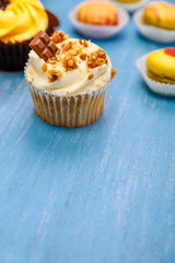 Cupcakes with buttercream and macaroons. Almond macaron cookies. Sweet dessert cakes. On wooden table.