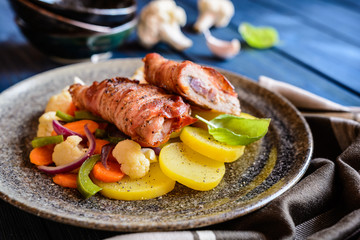 Fried pork cutlets wrapped in bacon and stuffed with onion and mustard, garnished with potato and steamed vegetable
