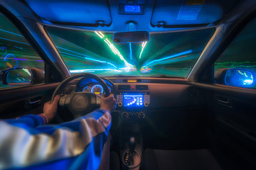 hands on the wheel a car moves at fast speed at the night. Blured road with lights with car on high speed