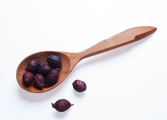 Dry berry Rose hips in wooden spoon isolated on white background