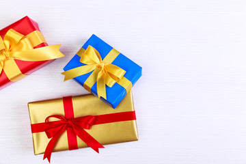Gift boxes with bow. Presents wrapped with paper and ribbons. Christmas or birthday packages. Celebration design. On white wooden table.