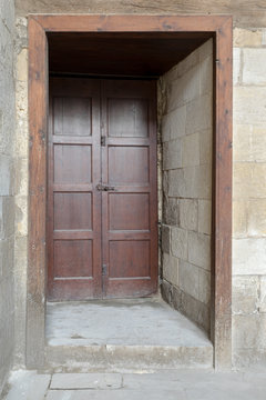 Recessed wooden aged engraved door and stone wall, Medieval Cairo, Egypt