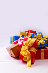 Gift boxes with bow. Colored presents wrapped with paper and ribbons. Christmas or birthday packages. Celebration design. On white table.