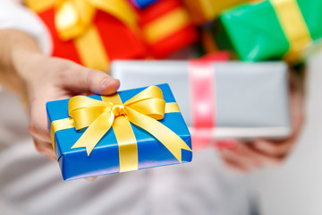 Male hands holding a gift boxes. Presents wrapped with ribbon and bow. Christmas or birthday packages. Man in white shirt give box.