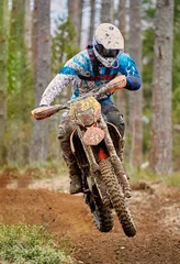 Foto op Aluminium Motocross driver jumping with the bike at high speed on the race track © Teemu Tretjakov