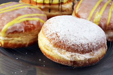 German donuts - berliner with jam and icing sugar in a tray on a grey background.
