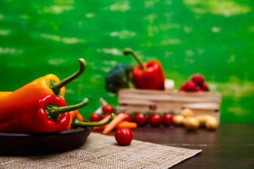 Sweet Peppers. Red and yellow vegetables. Fresh natural food in rustic bowl. Organic products on wooden table with sackcloth.