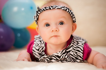A small baby girl is photographed in a beautiful dress for 4 months