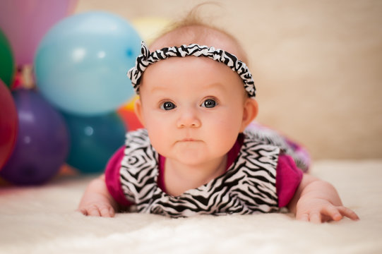 A small baby girl is photographed in a beautiful dress for 4 months