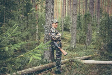 Crédence de cuisine en verre imprimé Chasser Hunter having rest in forest during hunting season